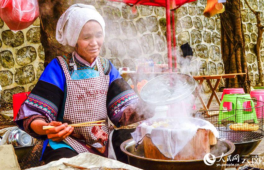 多依河のほとりで布依族の特色豊かなグルメ「花米飯」を作り、販売する布依族の女性（撮影・劉怡）。