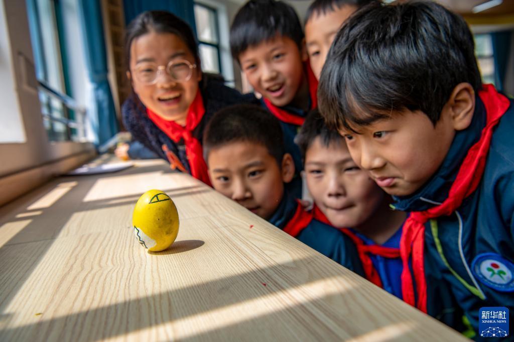 浙江省金華市婺城区の紅湖路小学校で、春分の日の風習である「卵立て」を体験する児童（3月20日撮影・胡肖飛）。