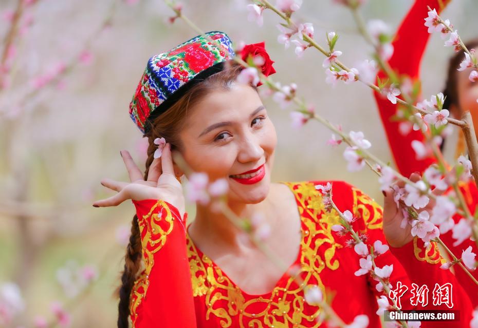 桃の林で桃の花を耳に飾る新疆の女性。