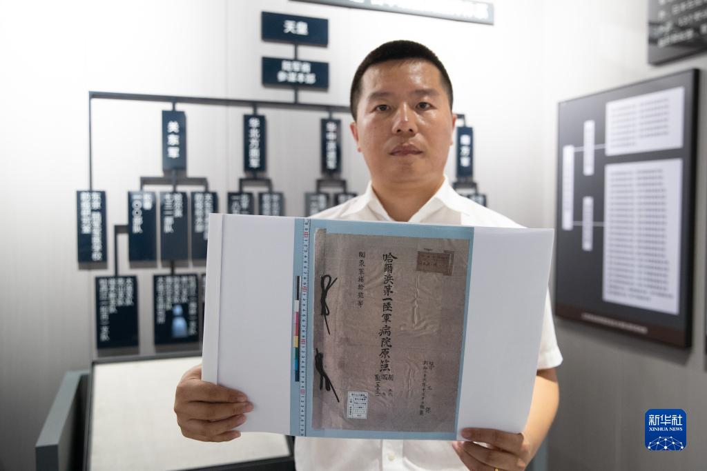 8月5日、黒竜江省牡丹江市で開催された中国侵略日本軍細菌戦罪証展示会で、「日本軍哈爾浜第一陸軍病院原薄」のコピーを示す研究者（撮影・張涛）