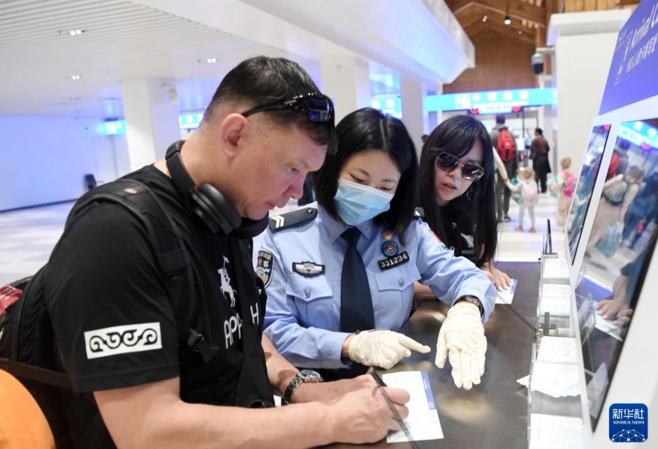 三亜鳳凰国際空港で、スキャットエアラインズDV473便でアルマトイから三亜に到着した旅客が入国関連書類を記入するのをサポートする鳳凰出入境辺防検査所の警官（1月31日撮影・趙穎全）。